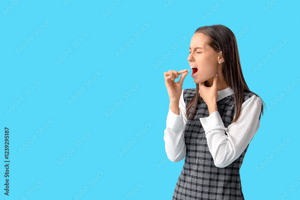 Young woman with pill for sore throat on blue background Young woman with pill for sore throat on blue background