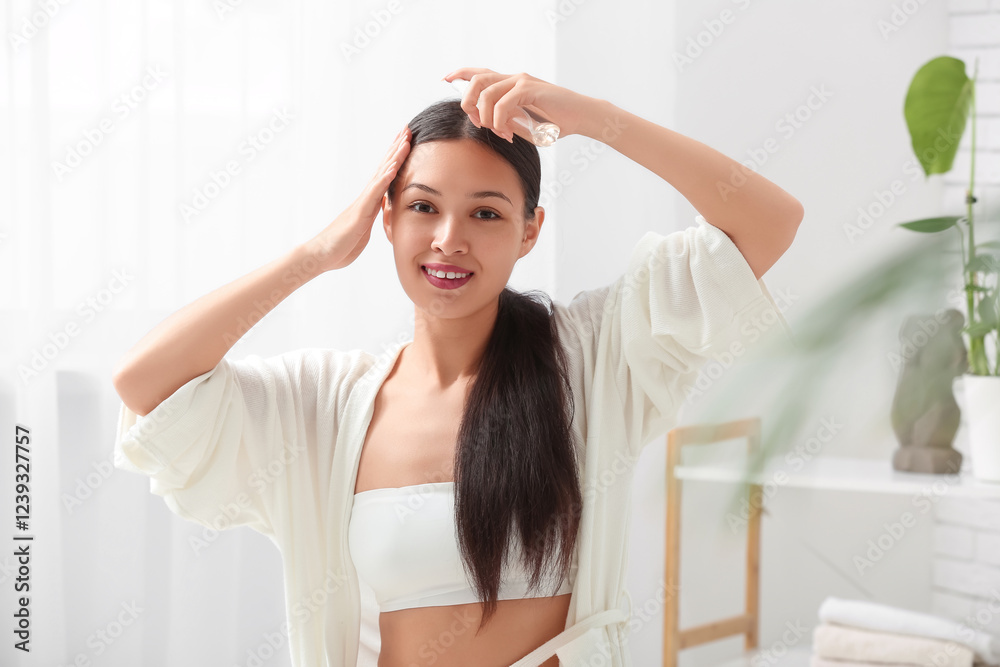 Beautiful young happy woman applying hair spray at home Beautiful young happy woman applying hair spray at home