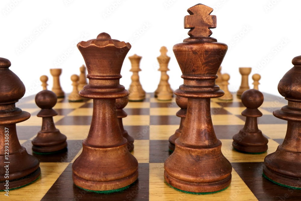 Close-up of the starting position in the chess game on wooden chessboard and chess pieces, view of the white opponent between the black queen and the black king through the chessboard Close-up of the starting position in the chess game on wooden chessboard and chess pieces, view of the white opponent between the black queen and the black king through the chessboard