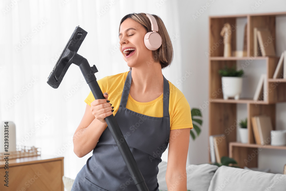 Beautiful young woman with headphones and vacuum cleaner singing at home Beautiful young woman with headphones and vacuum cleaner singing at home