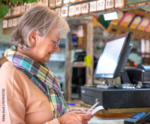 Senior white-haired woman checking the bill at the coffee shop before payment. Concept of modernity and online electronic payments photo