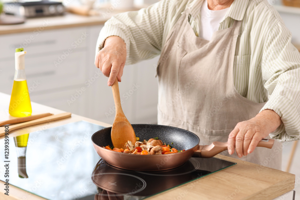 Senior woman frying vegetables in kitchen, closeup Senior woman frying vegetables in kitchen, closeup