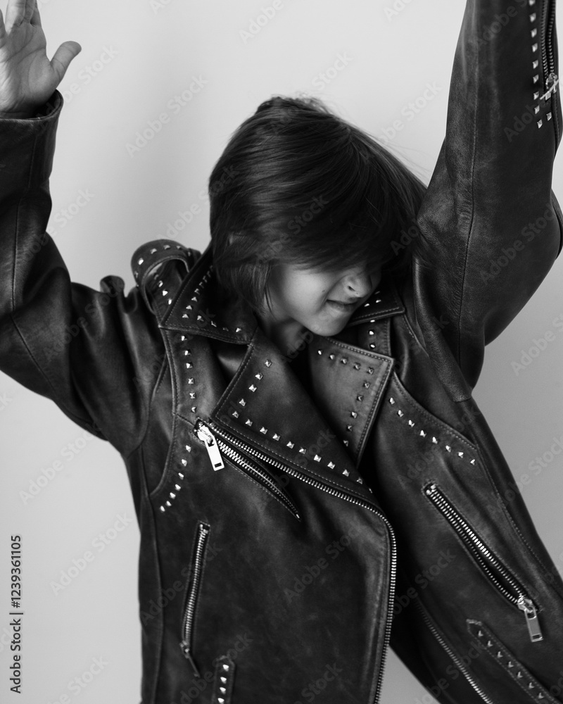 Portrait of an emotional 7-year-old boy in a large leather jacket posing in a studio. black and white photo.