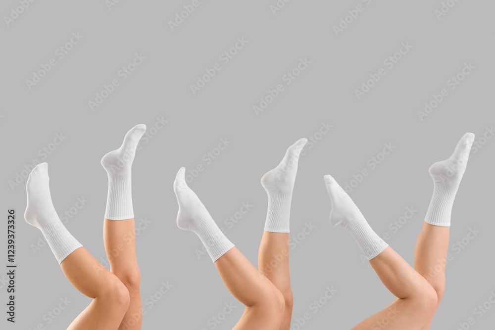 Legs of young women in white socks on grey background Legs of young women in white socks on grey background