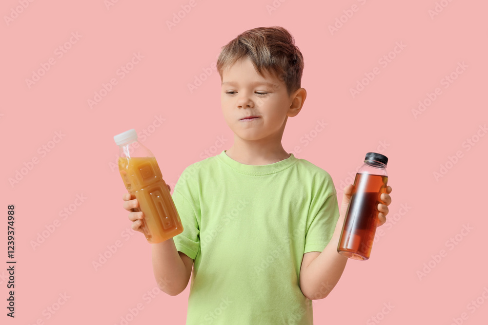 Thoughtful little boy with bottles of different juice on pink background Thoughtful little boy with bottles of different juice on pink background