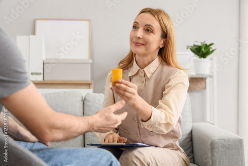 Female psychologist giving pills to drug addict in office