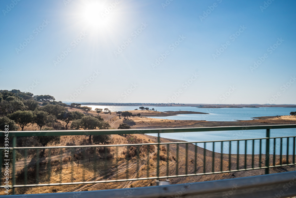 Blur of bridge railings with Alentejo landscape with trees and dry grass meadow on the banks of Alqueva (Grande Lago), PORTUGAL Blur of bridge railings with Alentejo landscape with trees and dry grass meadow on the banks of Alqueva (Grande Lago), PORTUGAL