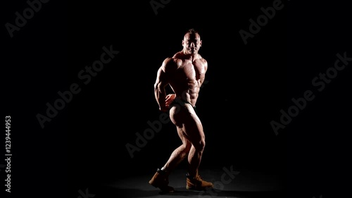 The athlete stands in boots, demonstrating not only musculature, but also confidence in his training. Clear muscle lines emphasize a high level of training.