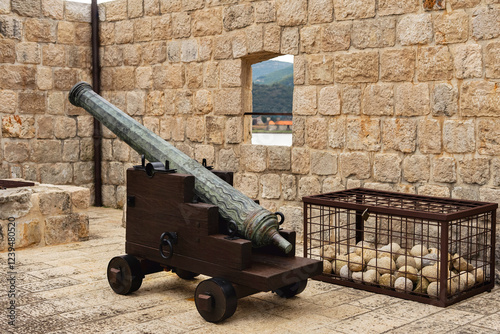 Historical cannon, in the town of Ston, Croatia. There are stone cannonballs lying next to it. Clouse up
