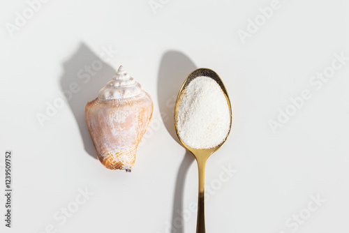 Marine collagen in golden spoon on white background