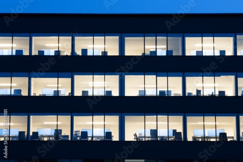 Modern office building with uniformly lit windows at dusk