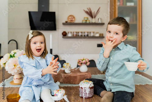 Children in the kitchen decorate Easter eggs with different colored sprinkles