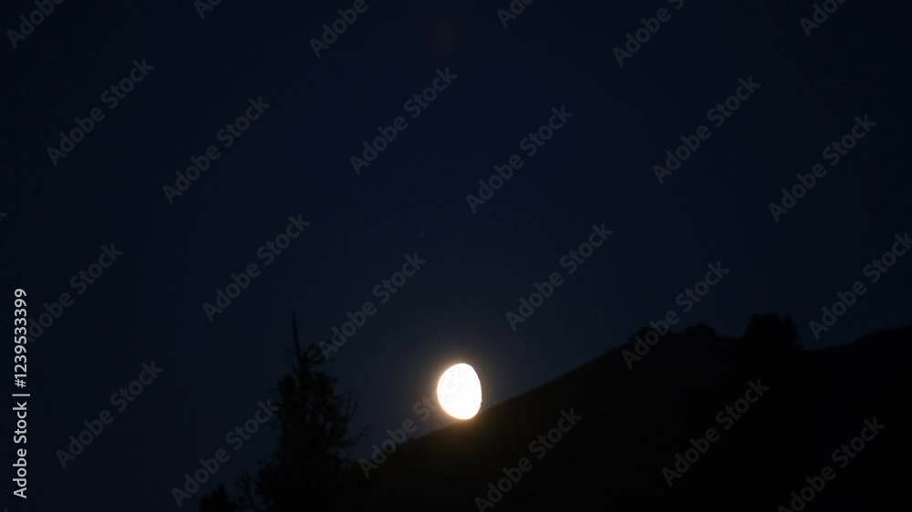 Full moon rising behind mountain ridge at twilight Full moon rising behind mountain ridge at twilight