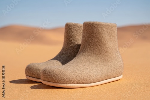 Cozy beige felt boots in desert sand with clear blue sky background photo