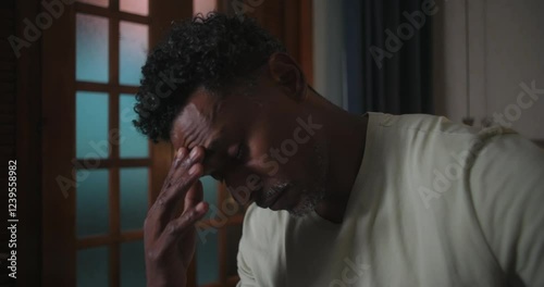 Man of African descent in close-up, hand on forehead, eyes closed, struggling with emotional distress, overwhelmed by anxiety, deep inner turmoil and mental exhaustion