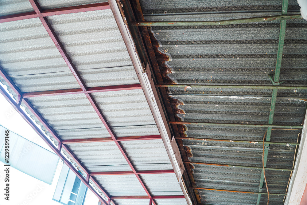 Fototapeta premium Image shows a severely damaged ceiling, revealing rusty metal supports and broken plaster. Urgent repair is required. Damaged Ceiling Structure: Urgent Repair Needed