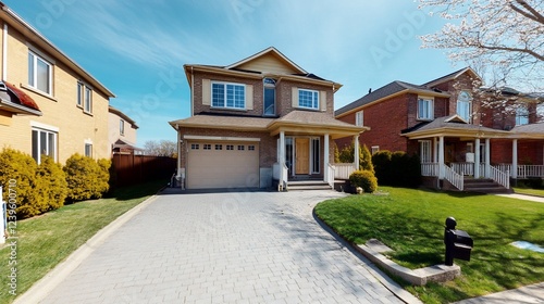Two-story suburban house with a driveway and manicured lawn on a bright day