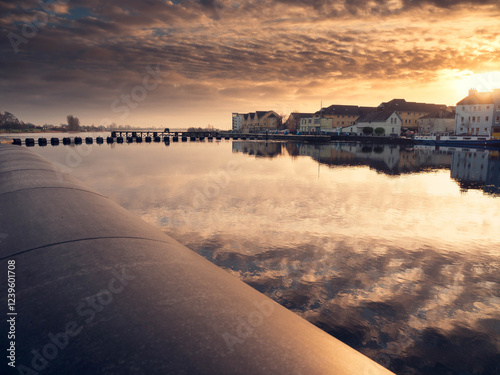 View on Riverside area of Athlone city, Ireland. Old town with long history and educational, shopping and industrial center. Warm sunset sky reflection in water. photo