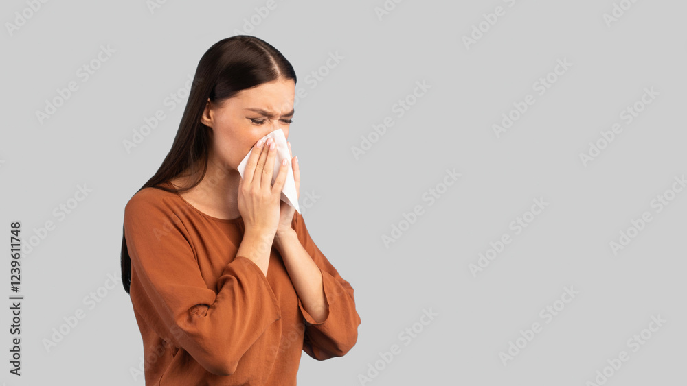 Cold And Flu. Sick Woman Blowing Runny Nose In Paper Tissue Having Rhinitis Symptom Standing On Blue Studio Background. Lady Sneezing Suffering From Allergy. Panorama, Empty Space