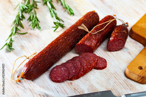 Fresh smoked russian sausage cut in slices on a wooden surface, close-up photo