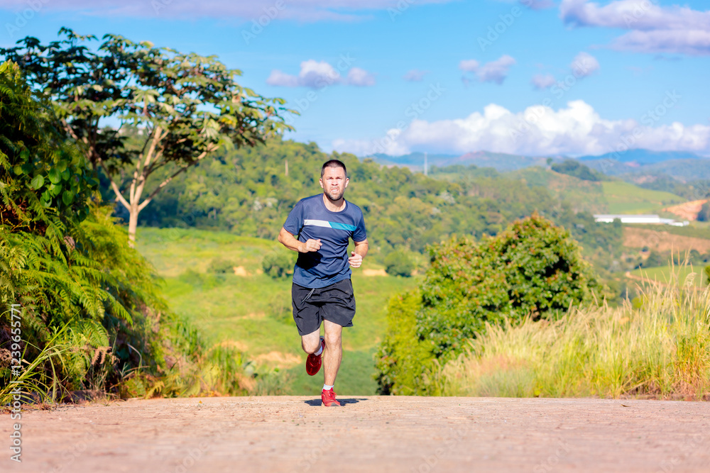 Brazilian man jogging on a scenic outdoor trail with lush green hills in the background. Concept of fitness, wellness, and an active lifestyle. Brazilian man jogging on a scenic outdoor trail with lush green hills in the background. Concept of fitness, wellness, and an active lifestyle.