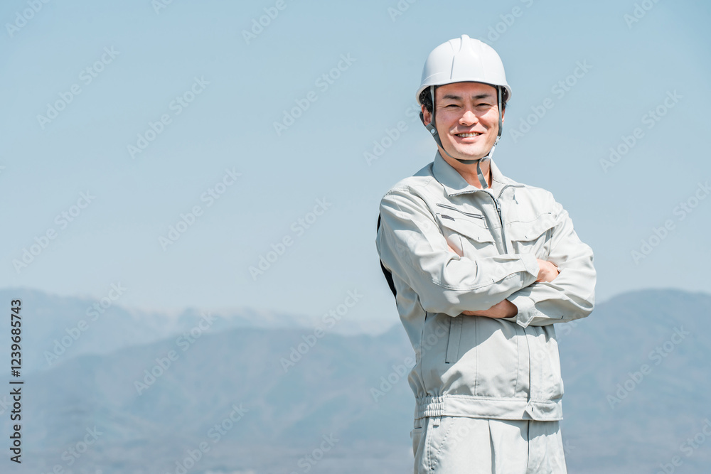 青空の下に立つヘルメットを被った作業着姿の男性(建築・土木・建設)
青空の下に立つヘルメットを被った作業着姿の男性(建築・土木・建設)