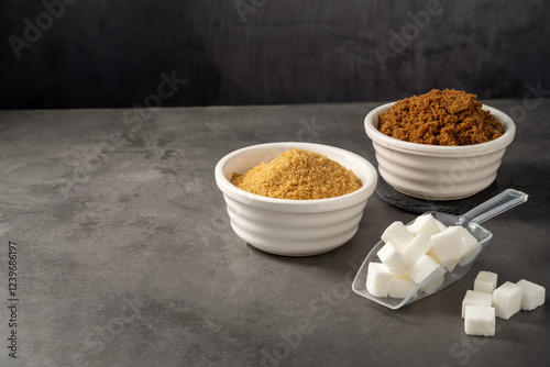Different type of sugar, light brown, dark brown and white sugar cubes in bowls. 