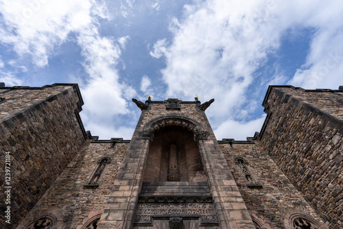 A majestic stone structure, possibly a church or castle, stands tall against a partly cloudy sky, its weathered stonework hinting at history.