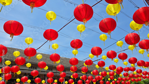 Vibrant red and yellow lanterns suspended across open balconies under a serene blue sky, representing festive celebrations of chinese new year and traditional cultural decor