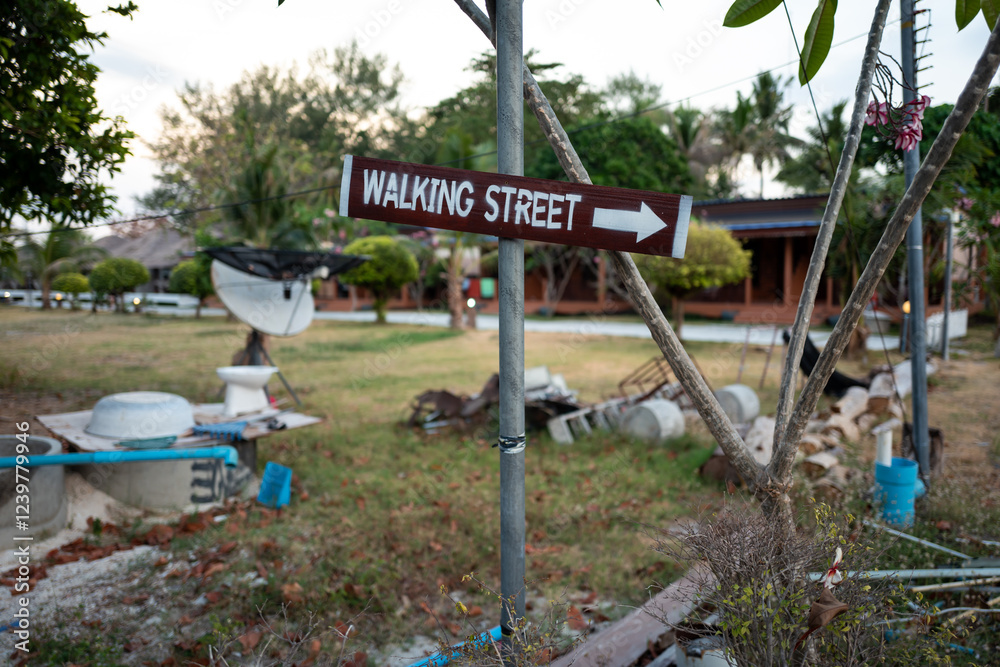 A weathered sign points the way to Walking Street, promising adventure in a tropical setting. A weathered sign points the way to Walking Street, promising adventure in a tropical setting.