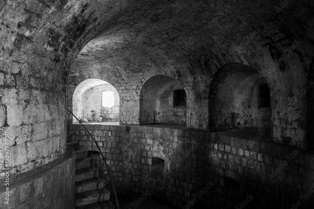 A descending stone staircase leads into a dimly lit, historic underground passage with arched alcoves.