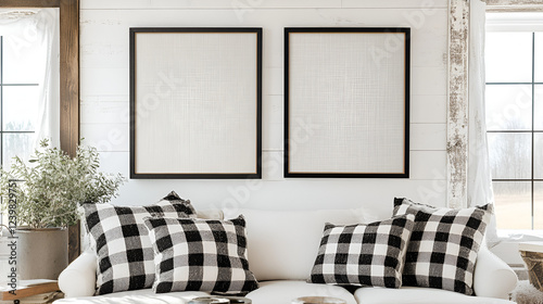 Farmhouse Living Room Mockup: Two blank black framed canvases hang above a cozy white sofa adorned with black and white buffalo check throw pillows, set against a rustic white shiplap wall.