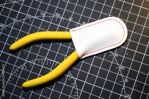 Closeup Yellow Nipper and white cap on black striped rubber cutting mat. Single blade nipper functions to cut plastic model kit parts. Metal tools for robot model kit hobbyists. Negative Space photo