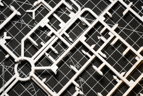White plastic model kit runner frame on black cutting mat. Remaining plastic runner frame after cutting model kit parts. Wallpapers Backgrounds. Abstract Texture. White and black colours