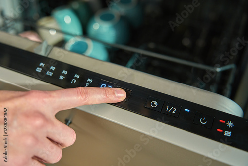 Obraz na płótnie Close-up of female finger pressing button on dishwasher control panel. Woman using dishwasher in modern kitchen. Modern kitchen appliance with digital settings for efficient dishwashing w salonie