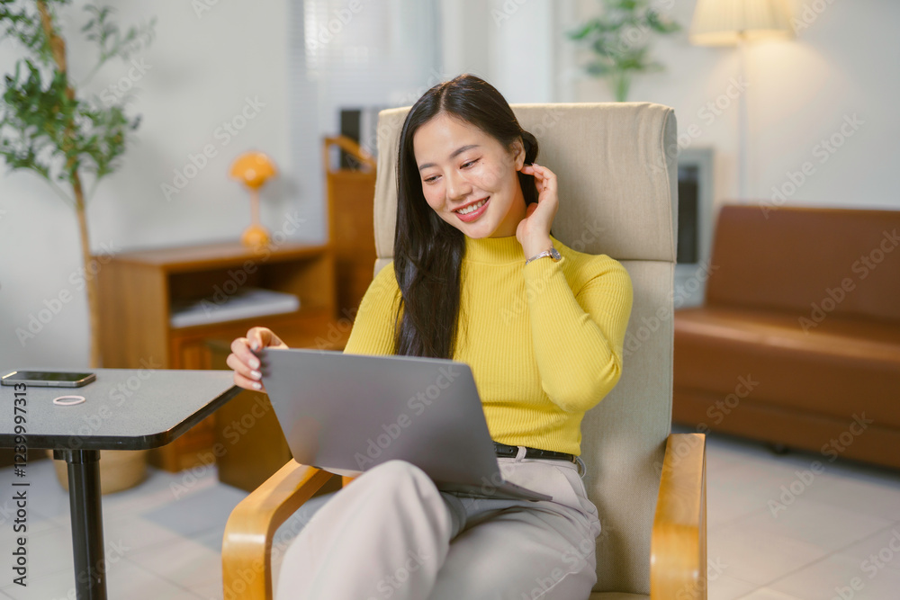Young Asian businesswoman using laptop and smiling while working from home Young Asian businesswoman using laptop and smiling while working from home