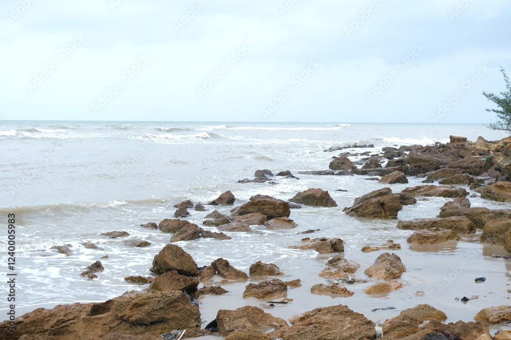 Fototapeta premium Rocky Beach Shoreline with Waves and Cloudy Sky