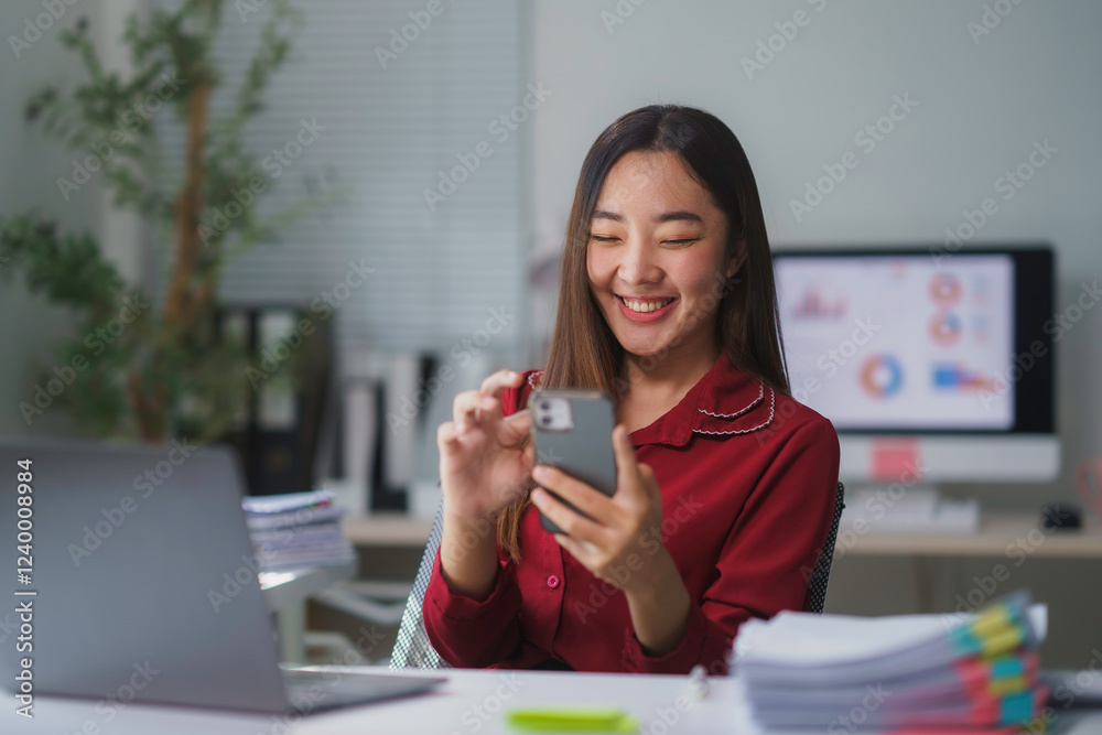 Asian businesswoman smiling and using smartphone in modern office Asian businesswoman smiling and using smartphone in modern office