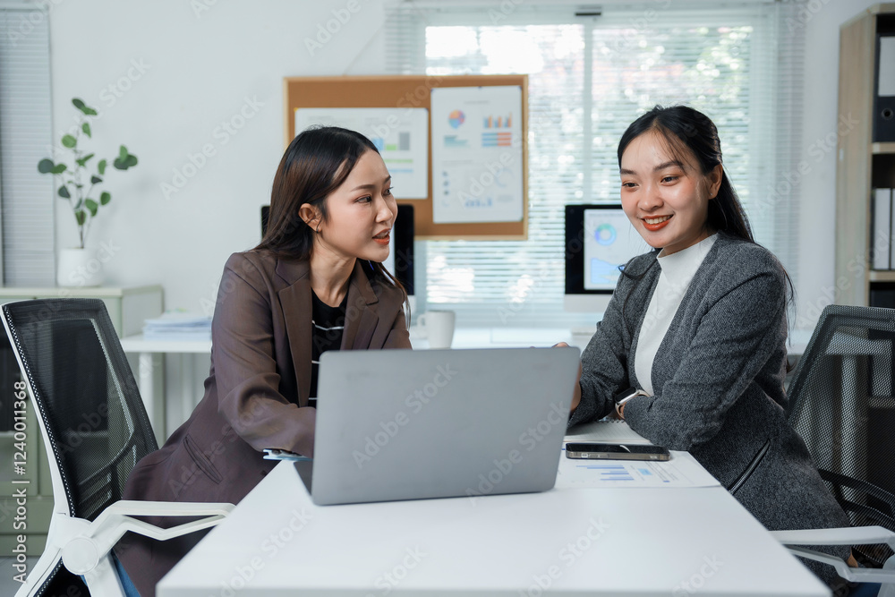 Two businesswomen discussing work using laptop in modern office Two businesswomen discussing work using laptop in modern office