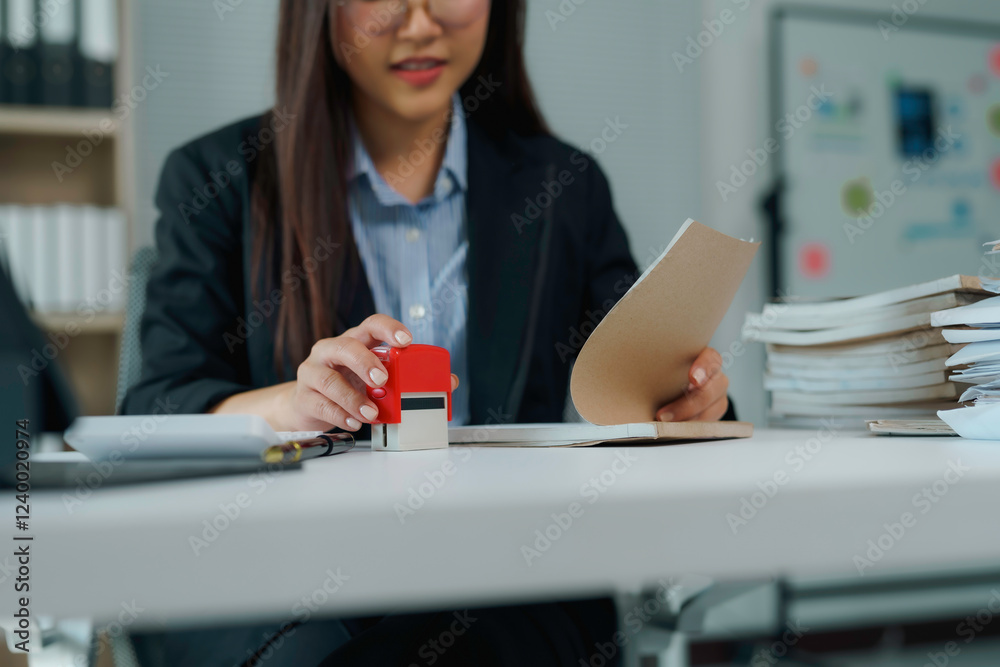 Businesswoman stamping document at office desk Businesswoman stamping document at office desk