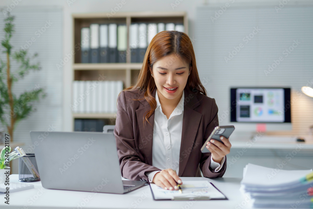 Asian businesswoman working with documents and using smartphone in office Asian businesswoman working with documents and using smartphone in office