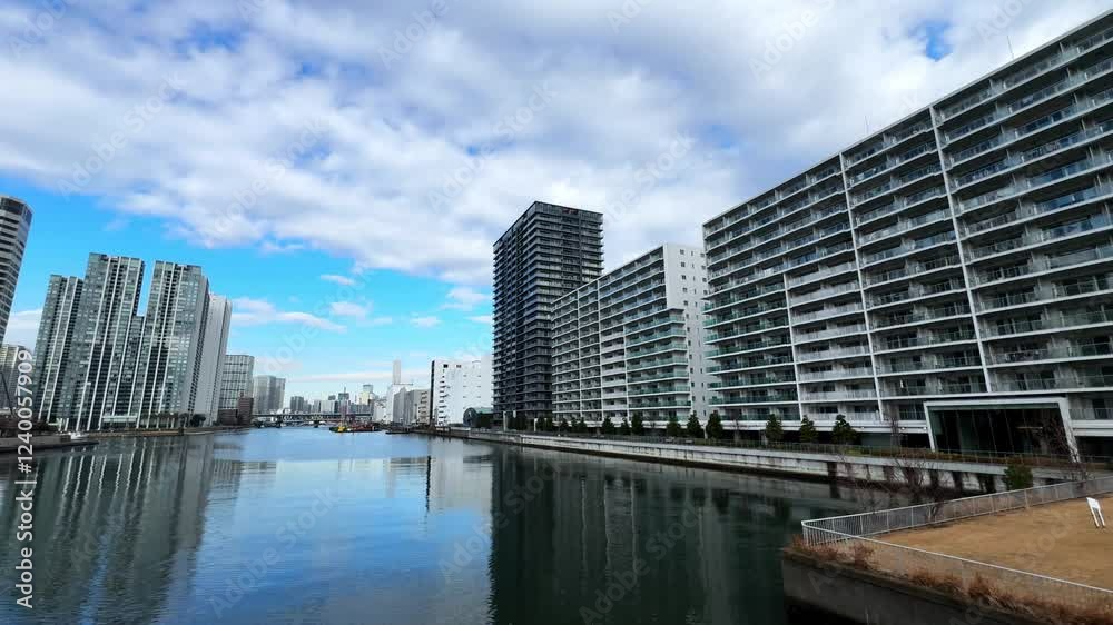 A calm canal in Tokyo with modern skyscrapers, a boat, and a partly cloudy sky A calm canal in Tokyo with modern skyscrapers, a boat, and a partly cloudy sky