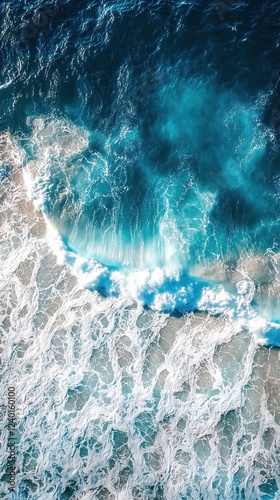 Aerial view of ocean waves crashing on shore with turquoise water and white sea foam