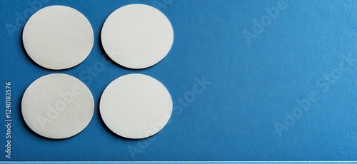 Four off white circular shapes arranged in a square pattern against a textured blue background. The circles are slightly raised, creating a subtle photo