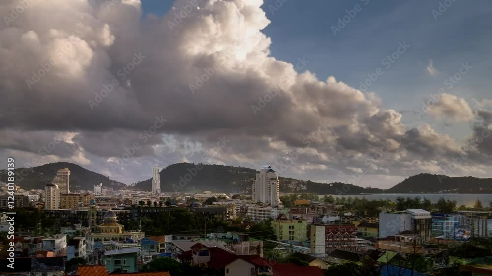 Dynamic timelapse over Patong, Phuket: Vibrant cityscape nestled between lush mountains and azure sea. Dramatic rainy clouds roll across the sky, casting ever-changing shadows on the bustling Thailand Dynamic timelapse over Patong, Phuket: Vibrant cityscape nestled between lush mountains and azure sea. Dramatic rainy clouds roll across the sky, casting ever-changing shadows on the bustling Thailand