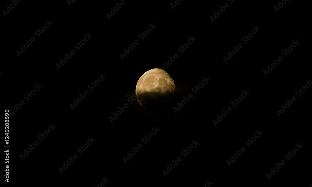 A photo of the full moon standing out against a black sky in clouds