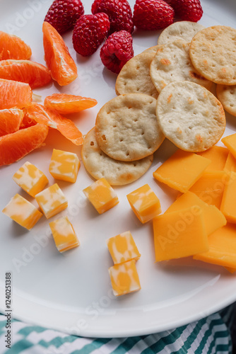 cheddar, colby jack, crackers, raspberries, orange segments on white plate