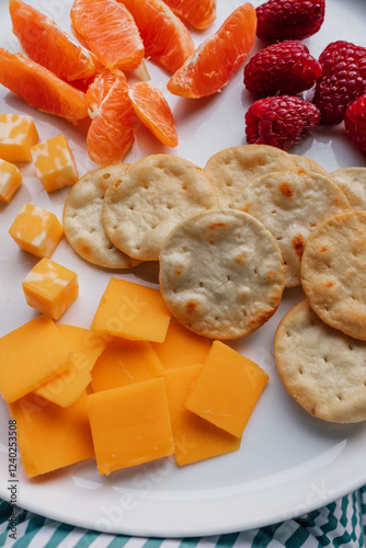 cheddar, colby jack, crackers, raspberries, orange segments on white plate