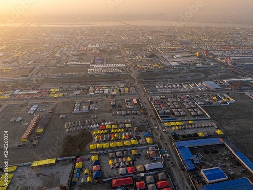 A stunning aerial view of Mahakumbh tent city at sunset, bathed in golden hues. The vast tents glow under the evening sky, creating a serene and spiritual ambiance over the sacred gathering.