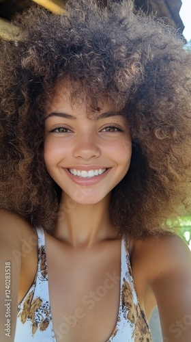 Bright smile of a young woman with curly hair indoors during daytime